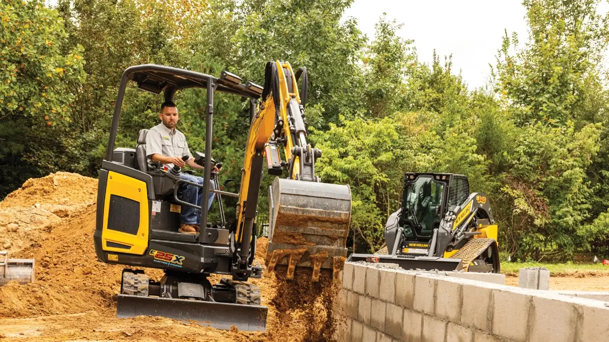 Operator digging near a wall with a mini excavator.