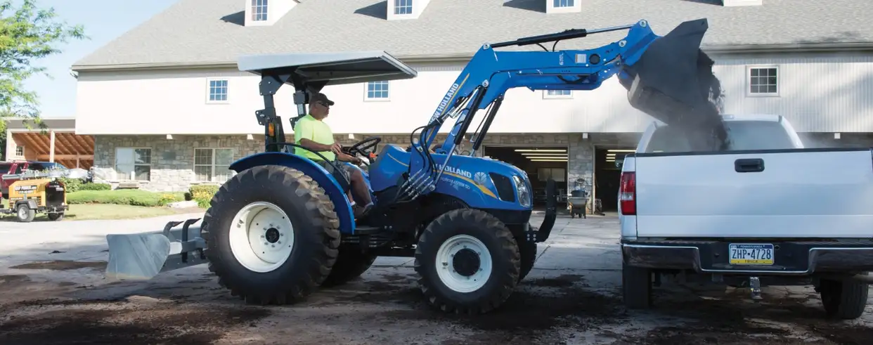 Operator uses WORKMASTER tractor front loader to dump material