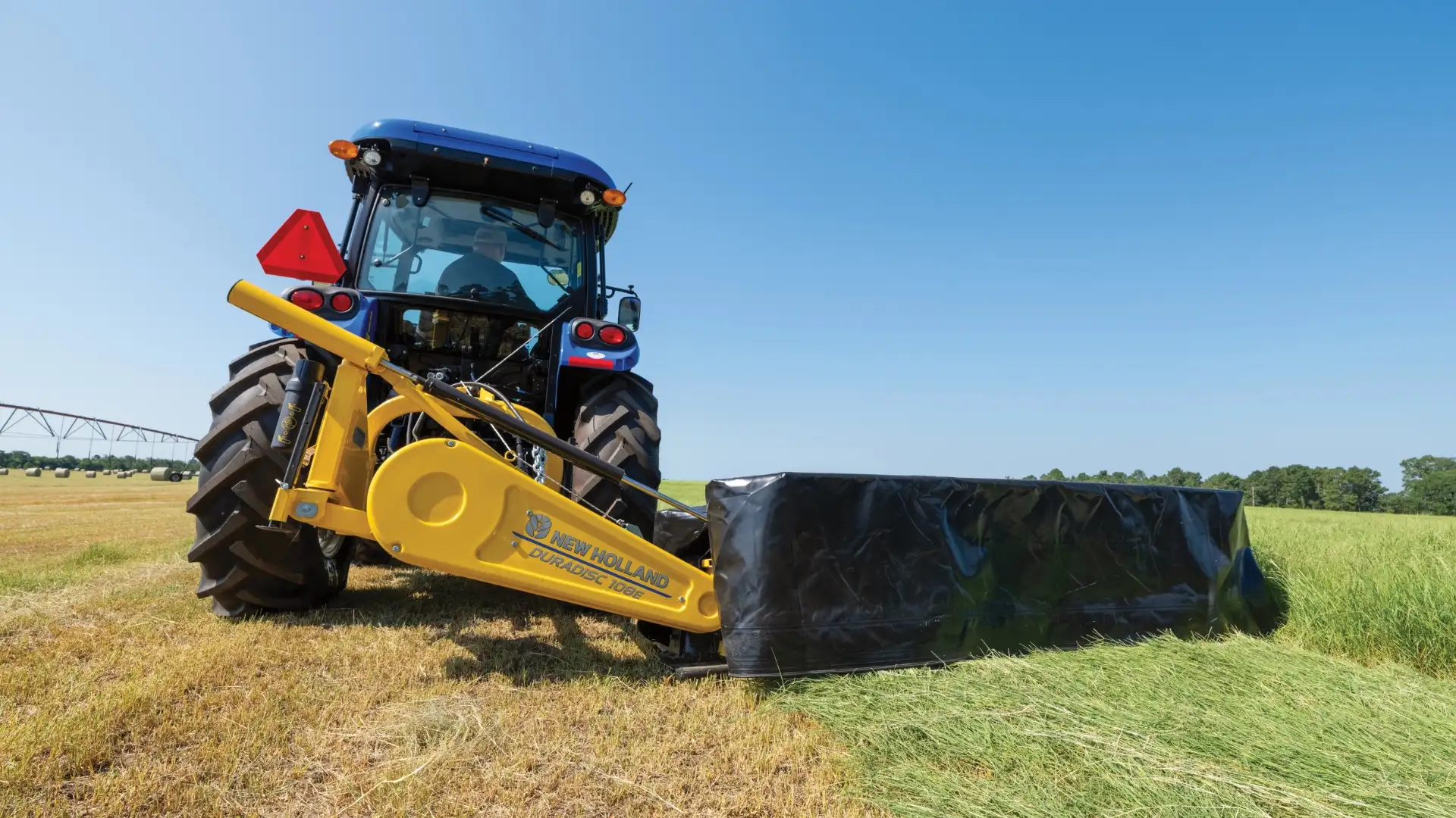 New Holland tractor pulling disc mower.