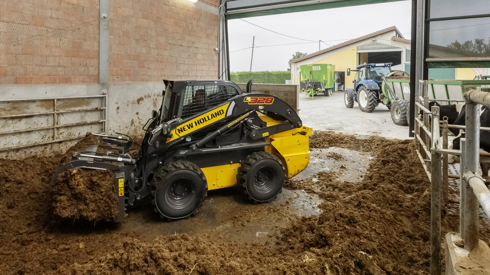 New Holland skid steer loader in barn, moving soil with claw attachment against brick wall backdrop.