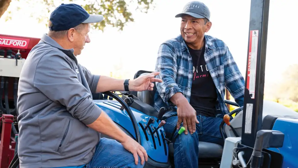 Men discuss farming on a New Holland tractor