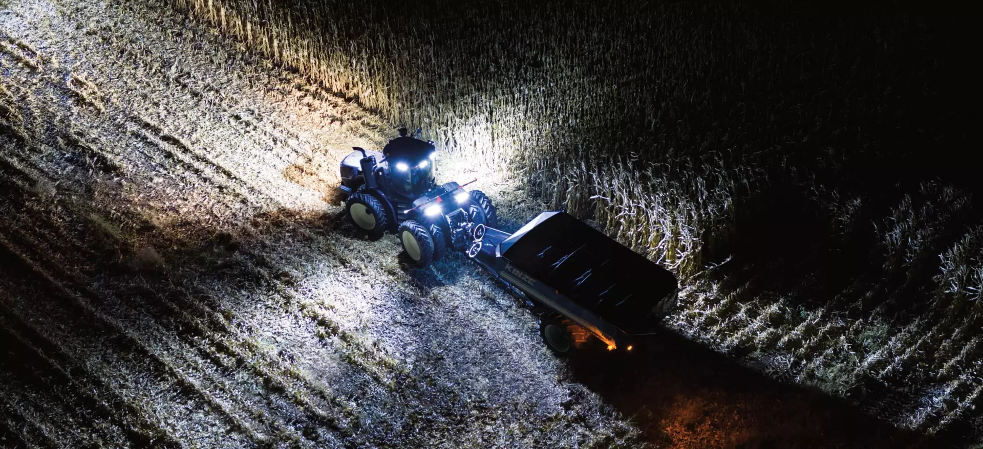 T9 with PLM Intelligence tractor in the field at night with lights illuminating path