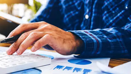 Man in a plaid shirt uses a calculator.