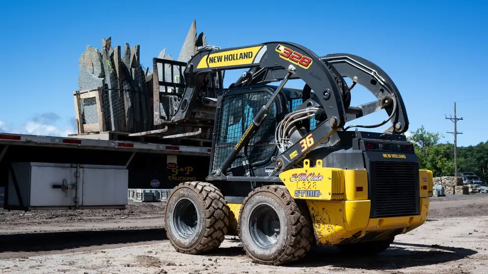 Skid Steer loader lifting pile of stone onto a truck bed.
