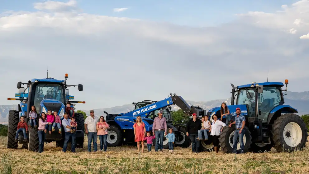 Family with T7 tractors and a TH7 telehandler in a field.
