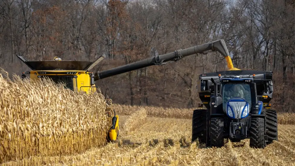 Combine and tractor work side by side in the field for harvesting
