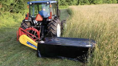 Tractor pulling a disc mower in a field.