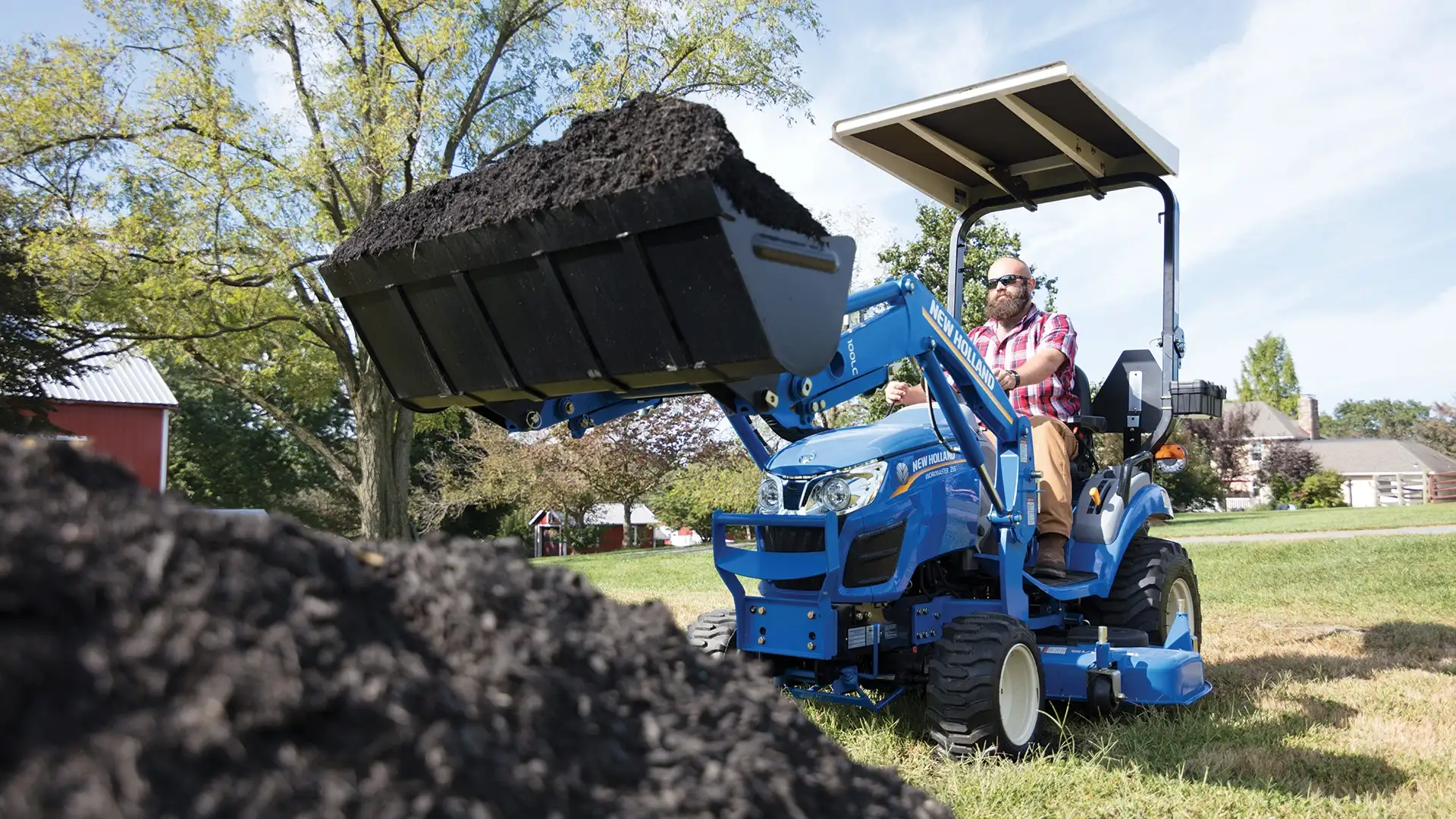 Man uses front loader on a WORKMASTER 25S tractor to move dirt