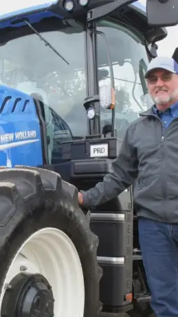Man standing in front of New Holland tractor.