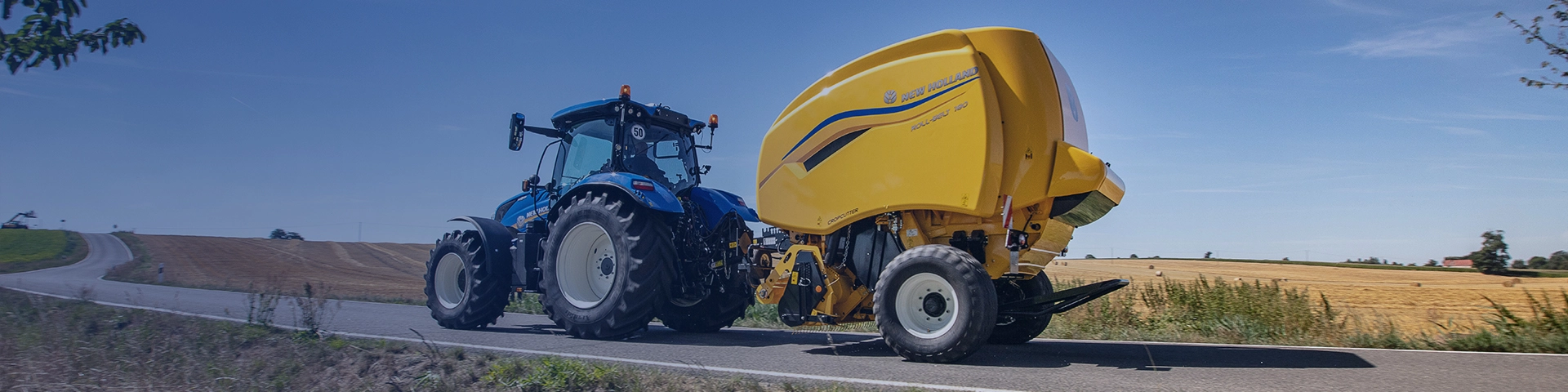 New Holland tractor with baler attached on the road