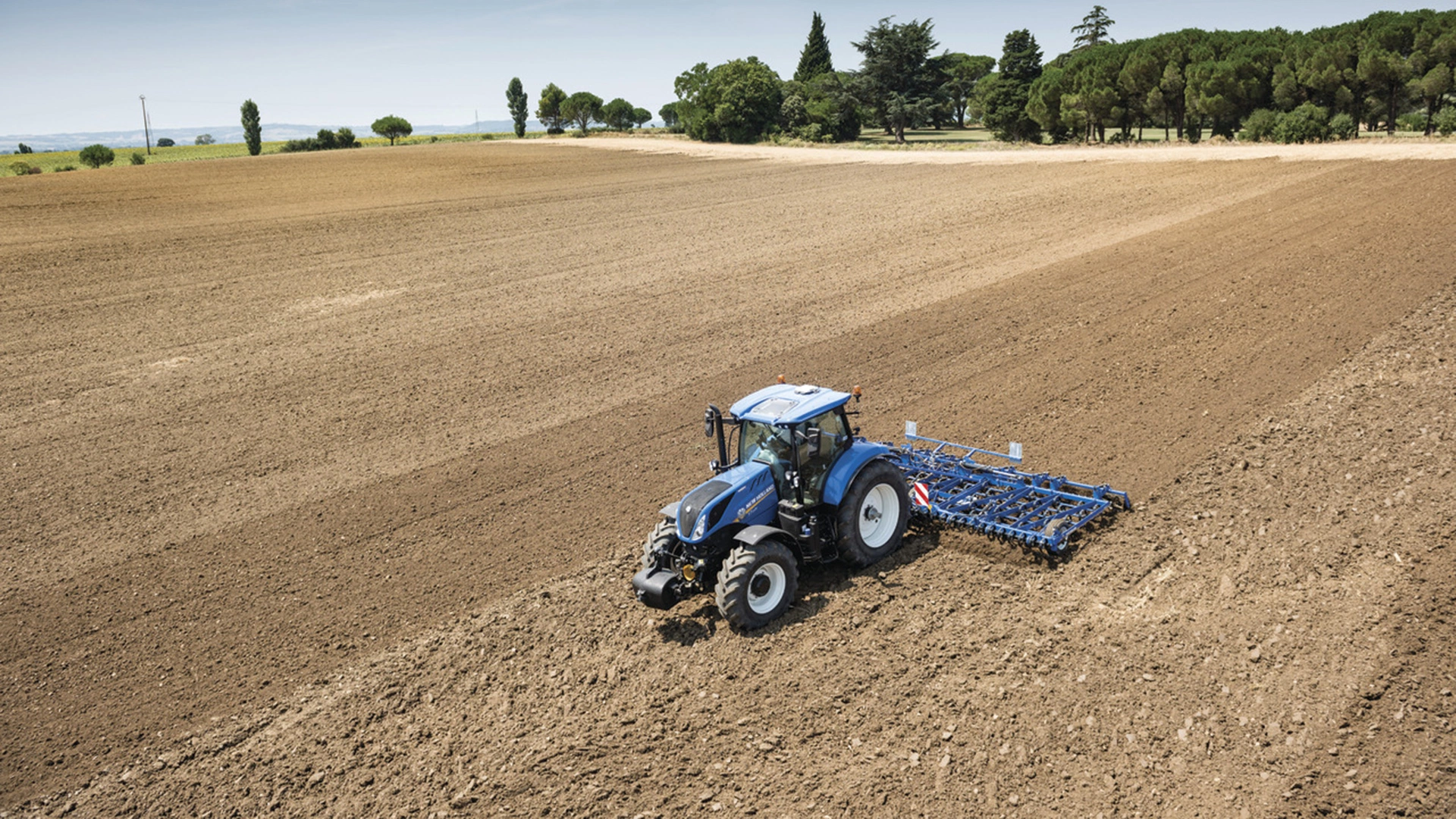 Productive farm landscape featuring New Holland tractor and seedbed cultivators working together