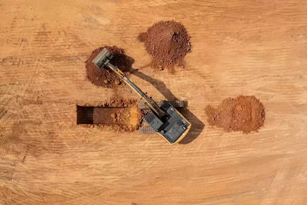 foto aérea da escavadeira hidráulica da Case Construction cavando a terra vermelha, com destaque para o movimento do guindaste.