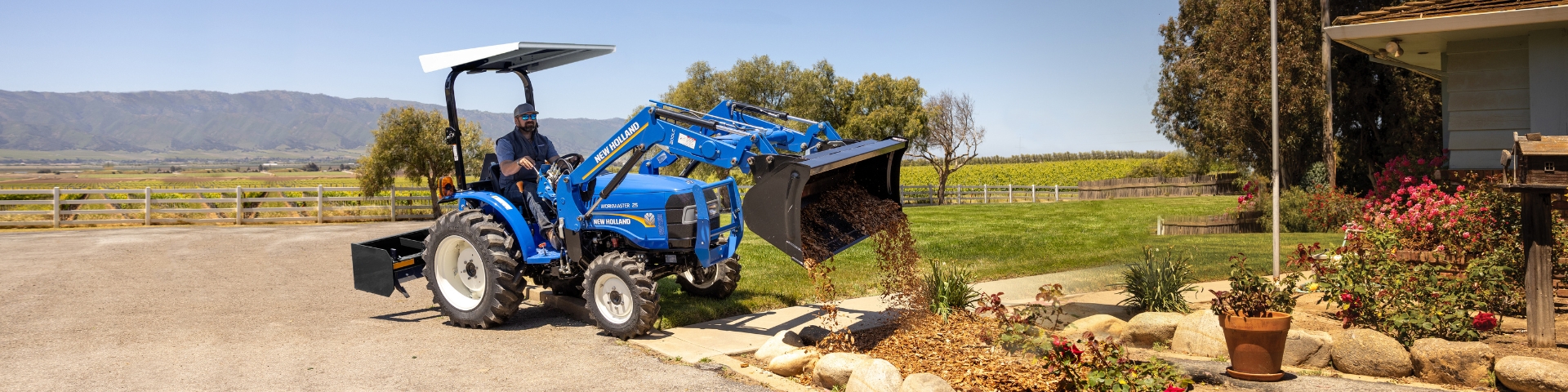 Blue tractor moving dirt in front yard.