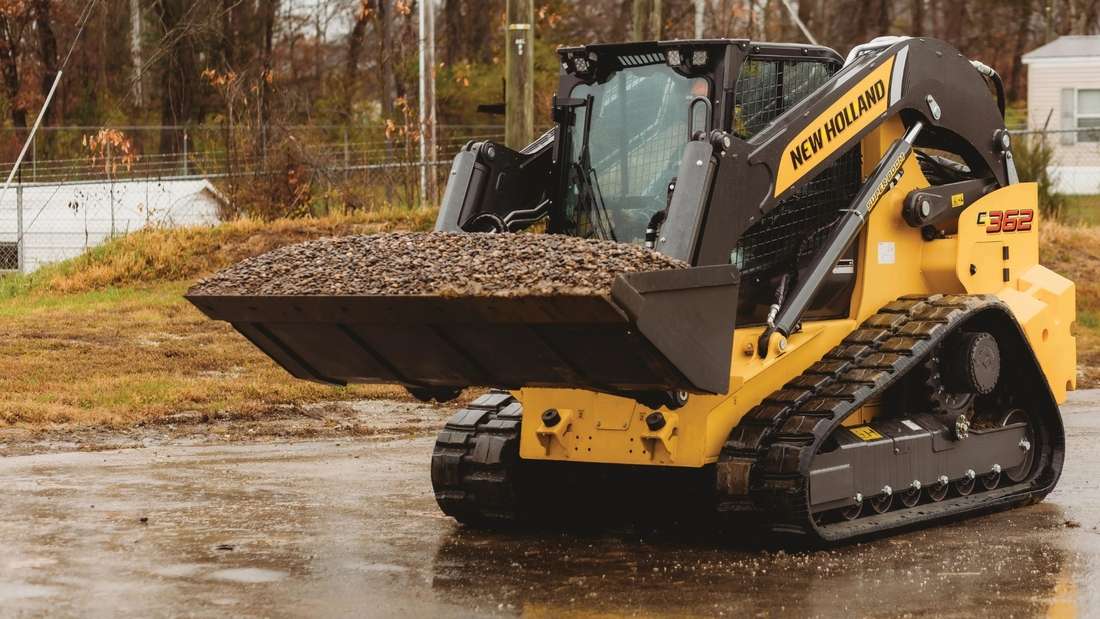 Compact track loader lifting dirt.