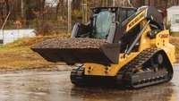 Compact track loader lifting dirt.