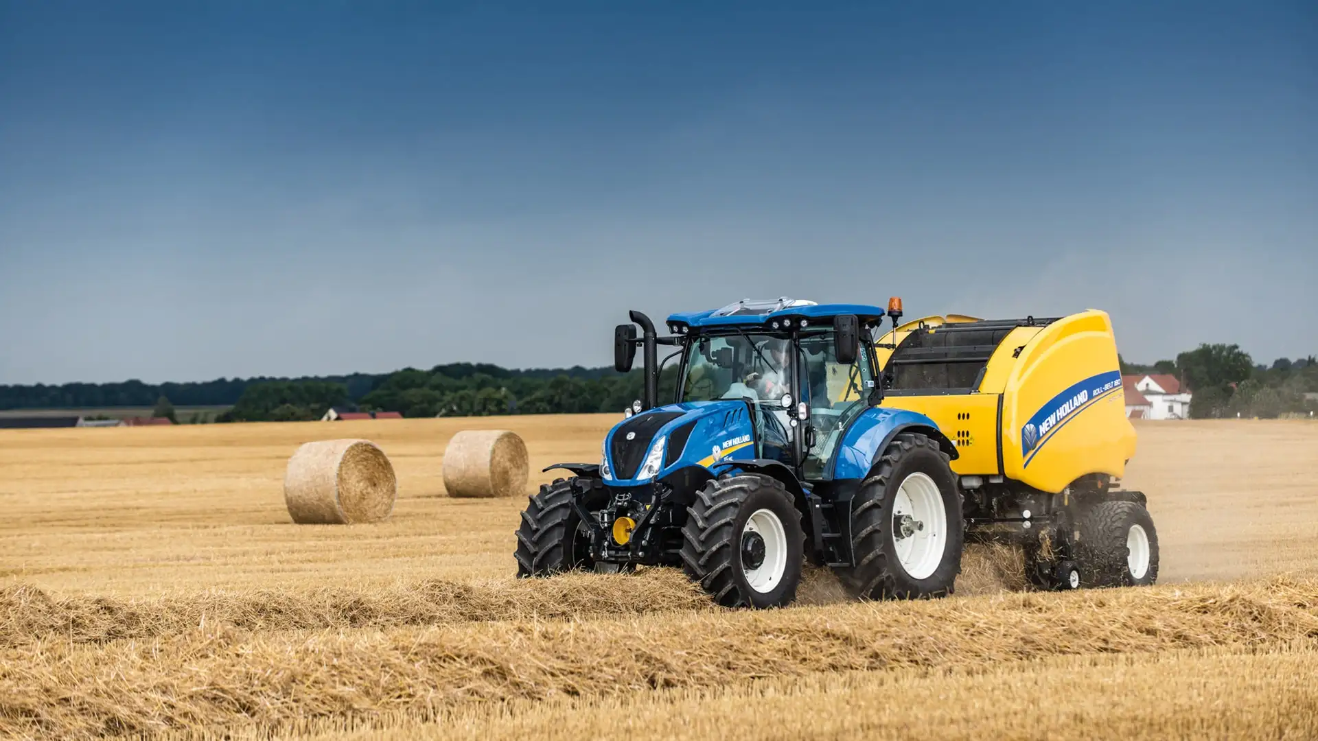 Tractor and Roll-Belt round baler combination actively bundling hay on the farmland