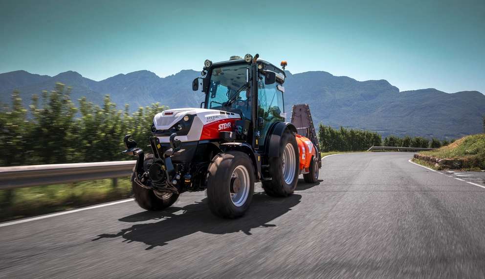 STEYR Spezial orchard tractor towing a sprayer along a mountain road