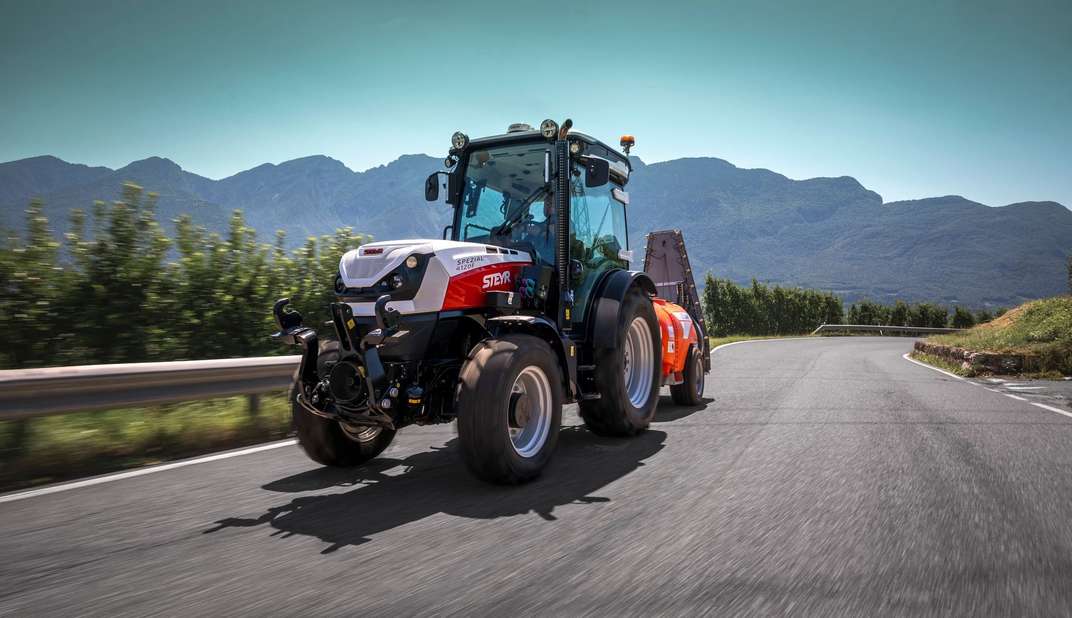 STEYR Spezial orchard tractor towing a sprayer along a mountain road
