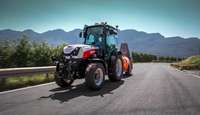 STEYR Spezial orchard tractor towing a sprayer along a mountain road