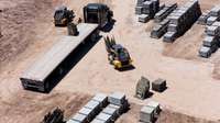 Skid steer loader lifting rocks onto truck.