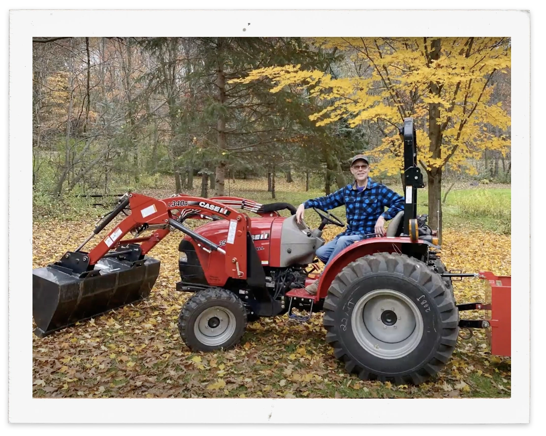 A man sitting on a new Farmall series tractor equipped with a L340 loader.