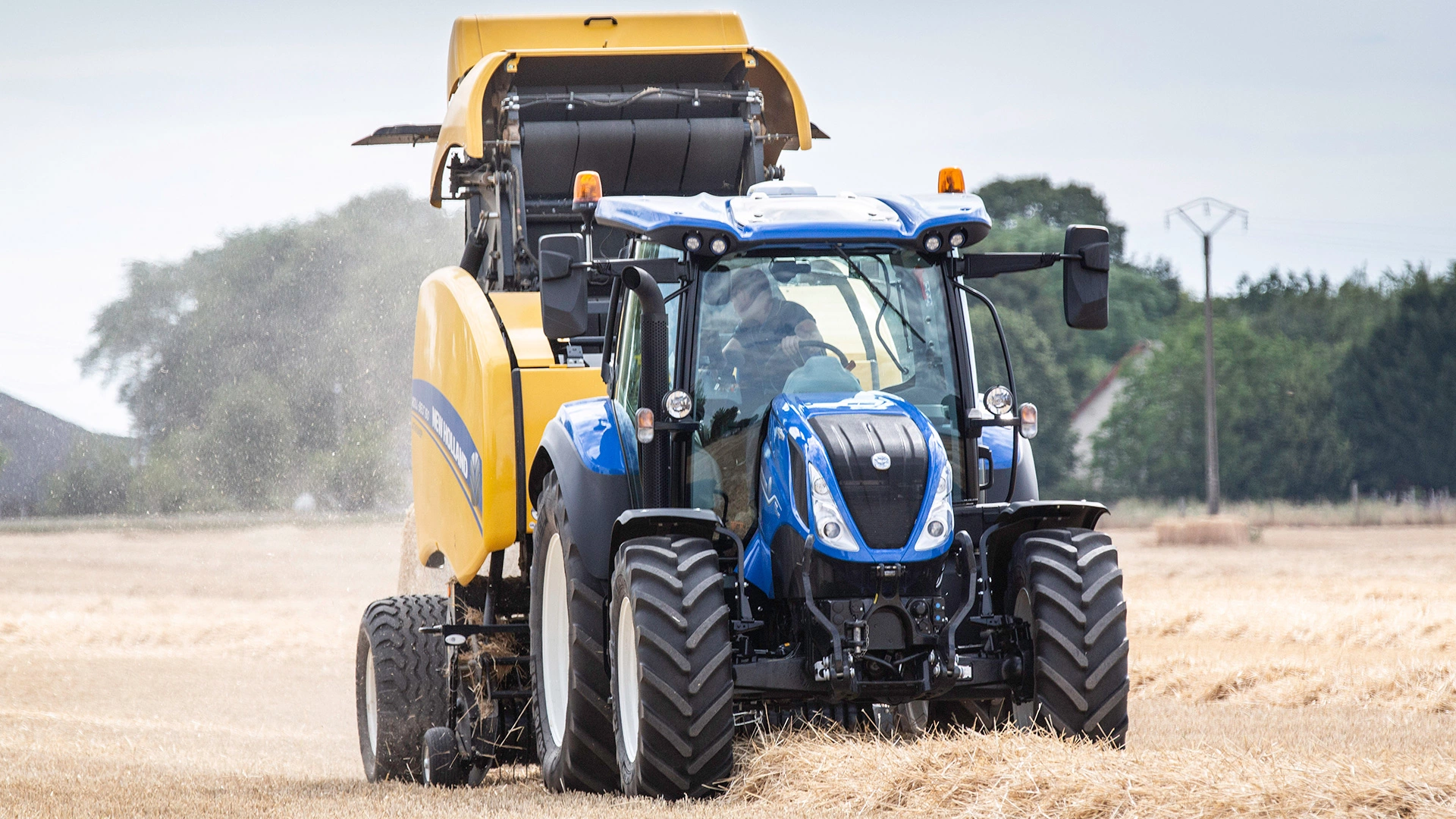 New Holland T5 Dynamic Command & Auto Command agricultural tractor with a baler