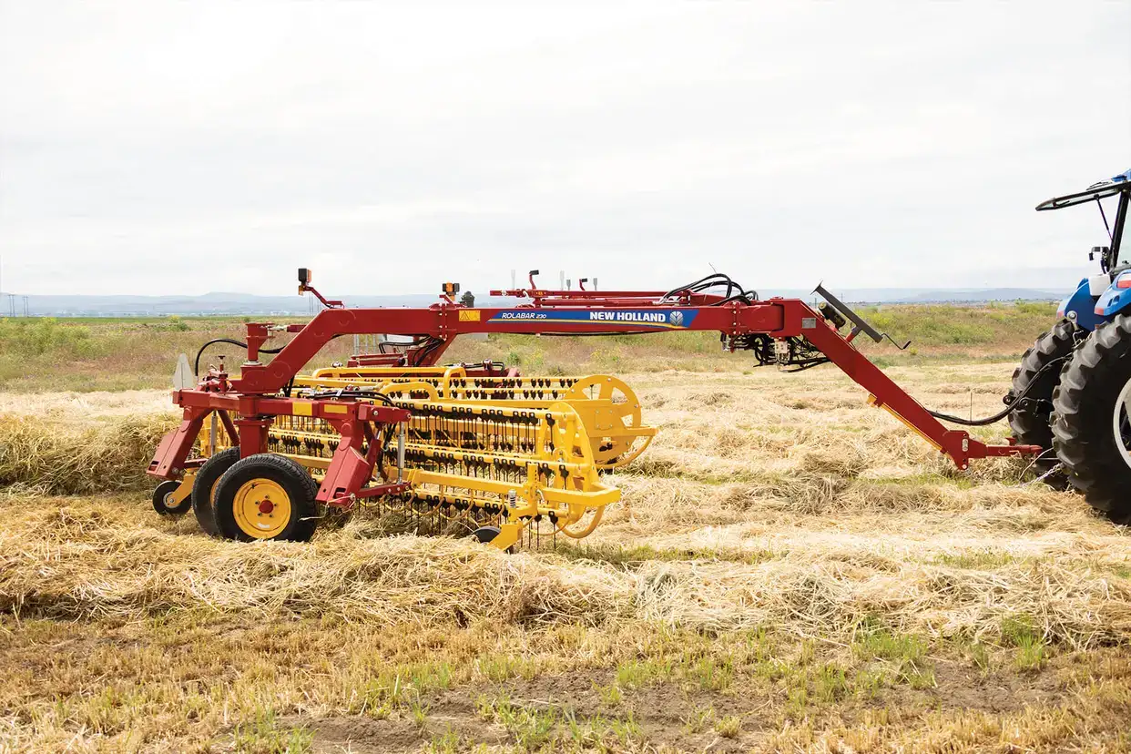 New Holland Rollbar rake 230 working in field with tractor