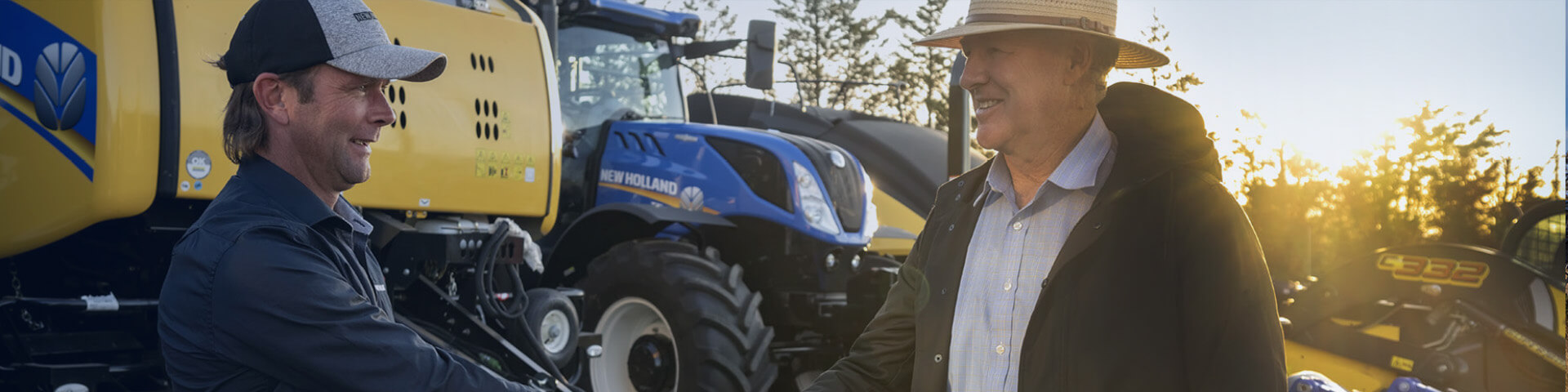 New Holland baler and tractor in background with two men shaking hands