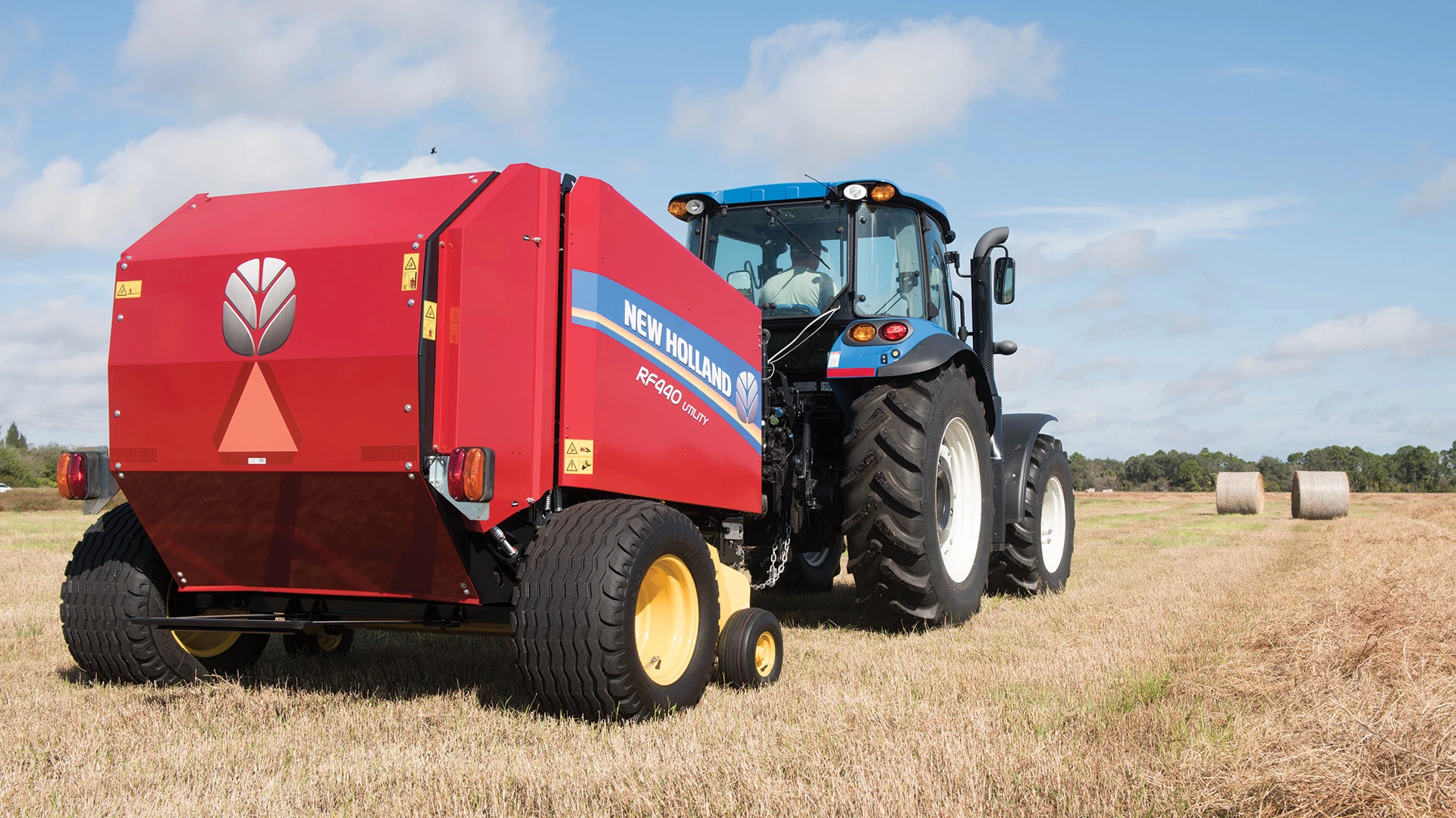 RF Fixed Chamber Round Baler pulled behind a New Holland tractor