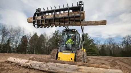 New Holland Construction Skid Steer Loader lifting logs with grapple/