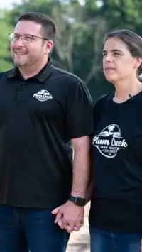 Couple standing in front of trees while holding hands.