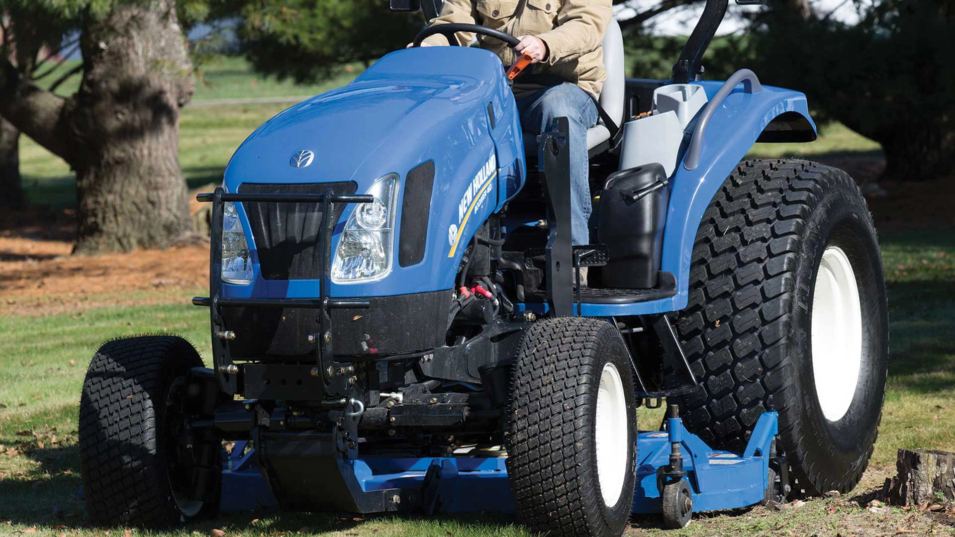 Blue Tractor Smoothing the Ground in a Farm with Trees and Grass