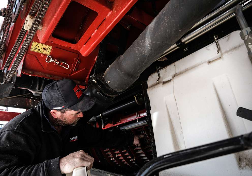 Case IH worker working on tractor, fitting oil filter to a tractor