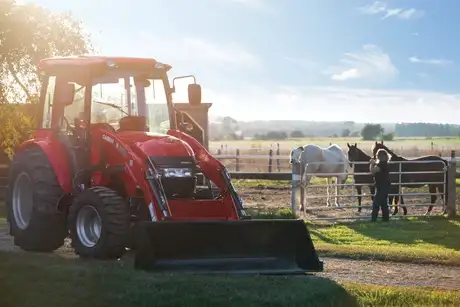 Farmall Compact 55C tractor with L360A Loader parked on a farm at sunset.