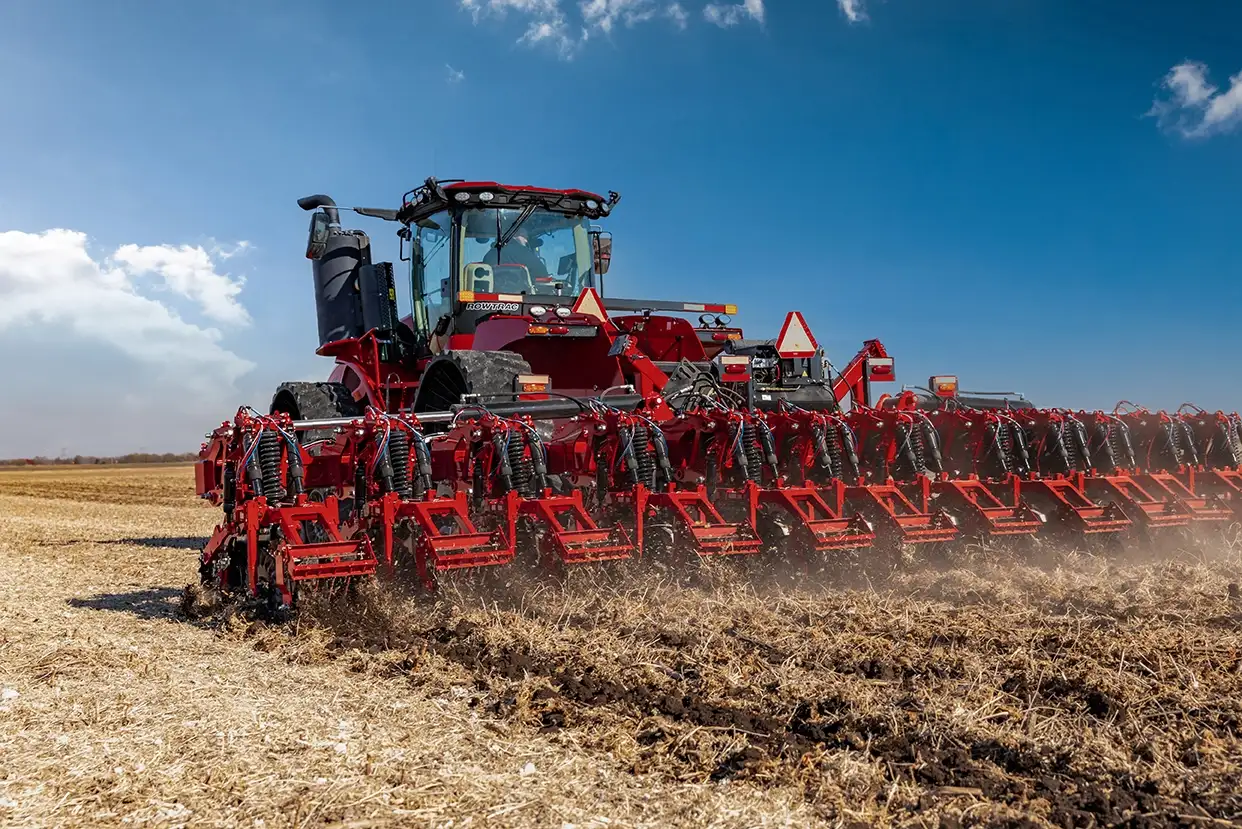 A Case IH tractor with Nutri-Tiller 1000 series strip tillage tool passes through a large field.
