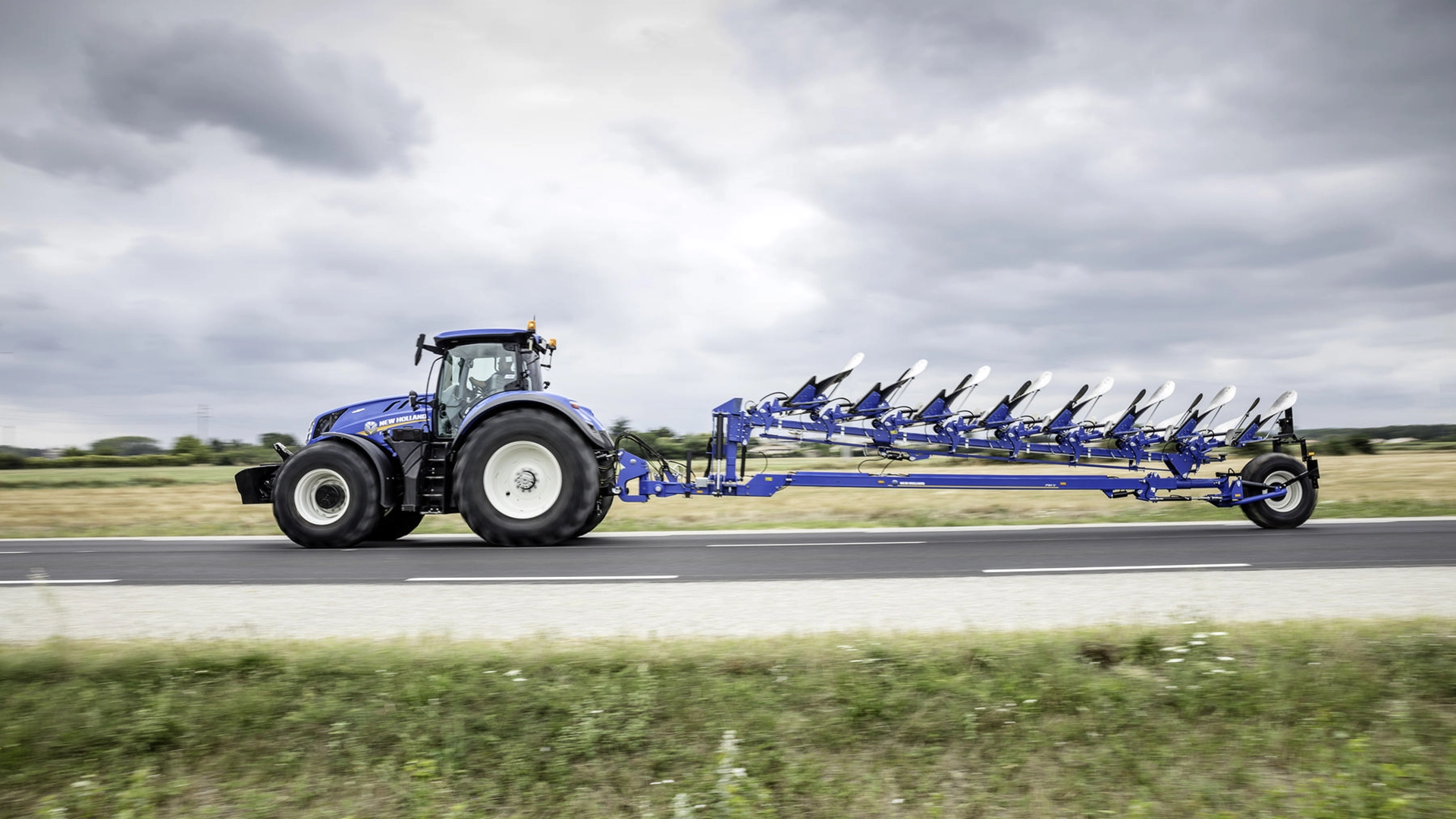 New Holland tractor ploughing with a agricultural plough on fertile land.