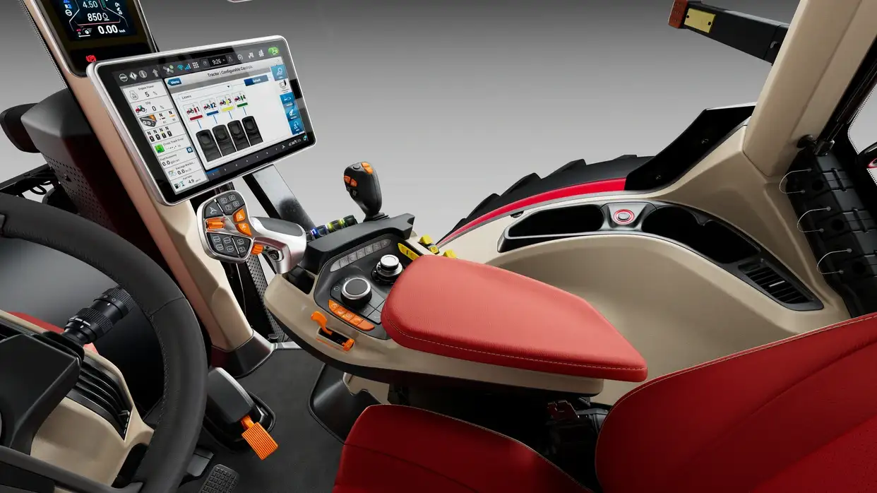 Case IH Optum tractor cab interior with a large touchscreen displaying controls, a steering wheel, red seat, and control levers, conveying advanced technology.