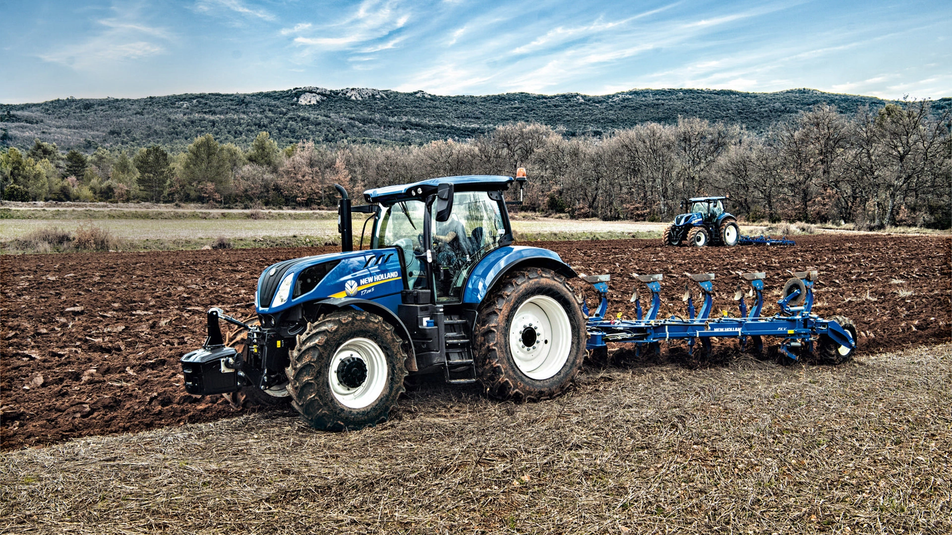 Tractor with a 5 furrow fully-mounted variable width reversible plough