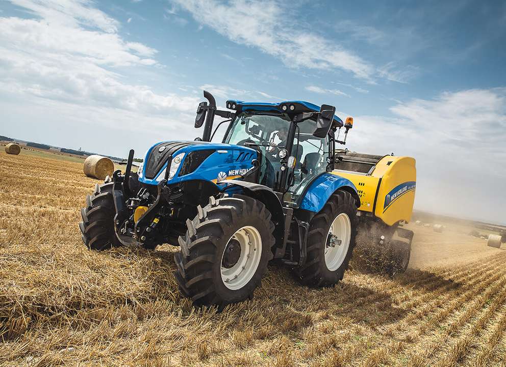 Blue New Holland T6 tractor working in filed with clear sky