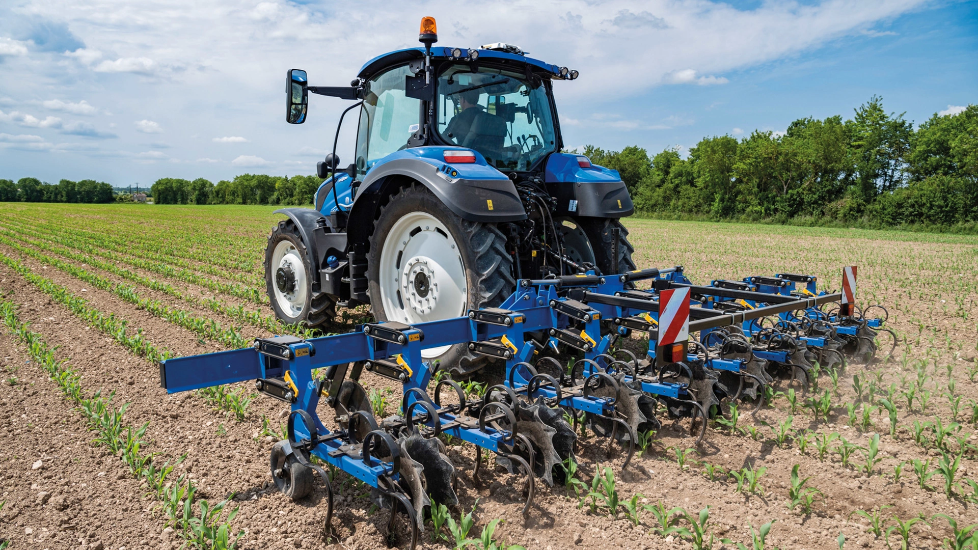 Tractor with SRC & SRC SmartSteer Interrow Cultivators in motion, cultivating the soil between green rows on a farm field