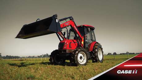 Red Case IH tractor sitting in farm on field with attachment bucket