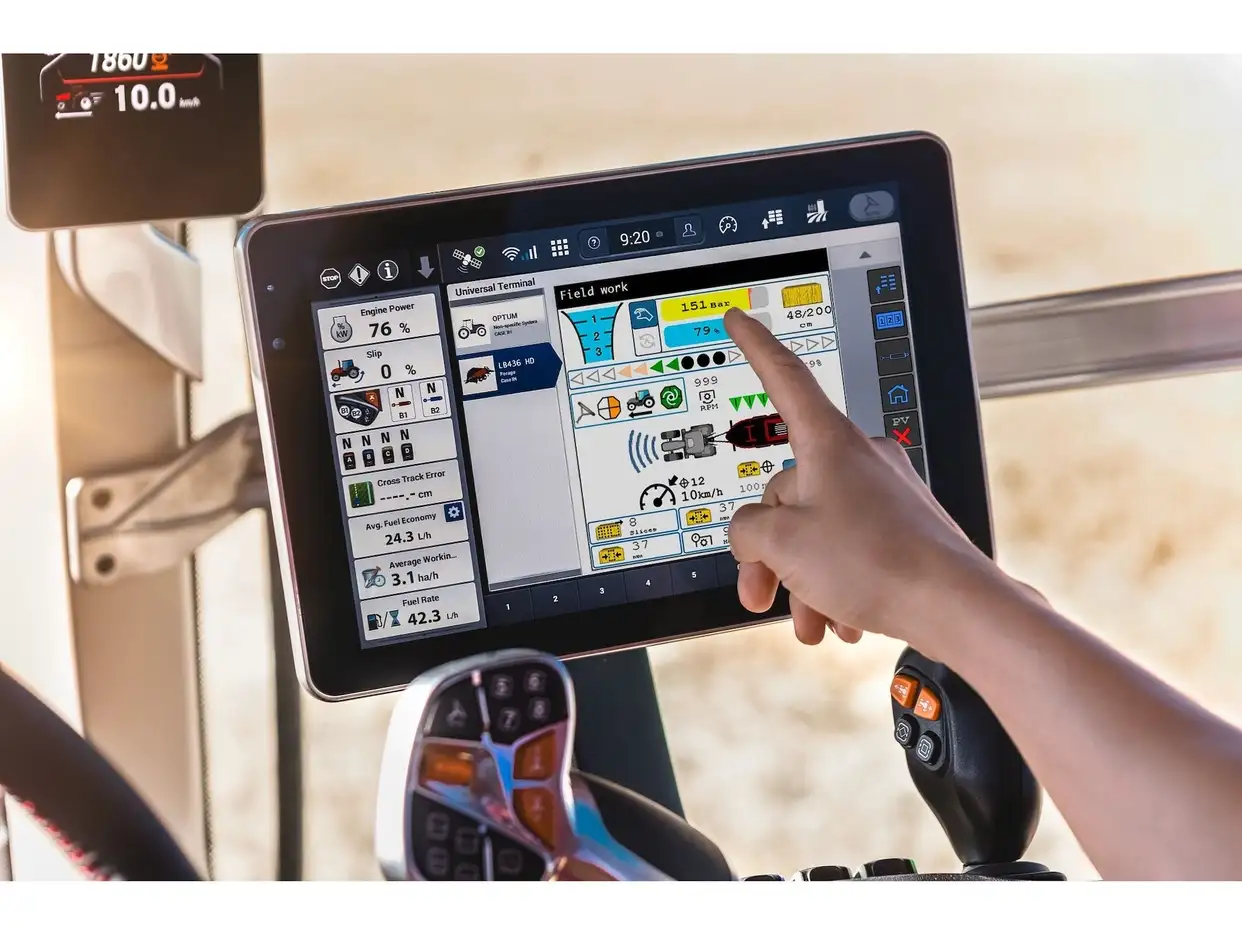 Operator interacting with the Case IH AFS Pro 1200 touchscreen display inside the cab showing field work data for the tractor and baler