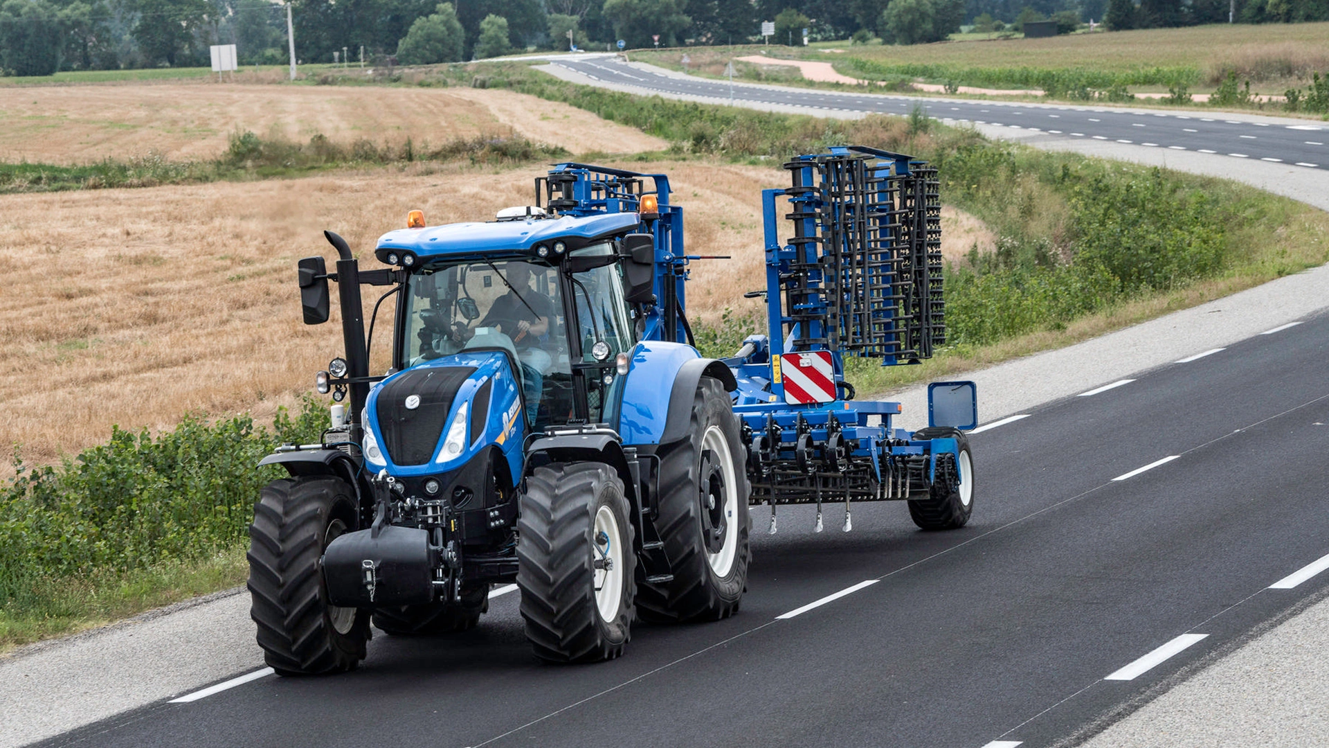 T7 LWB Farming Tractor transporting tilling equipment on the road