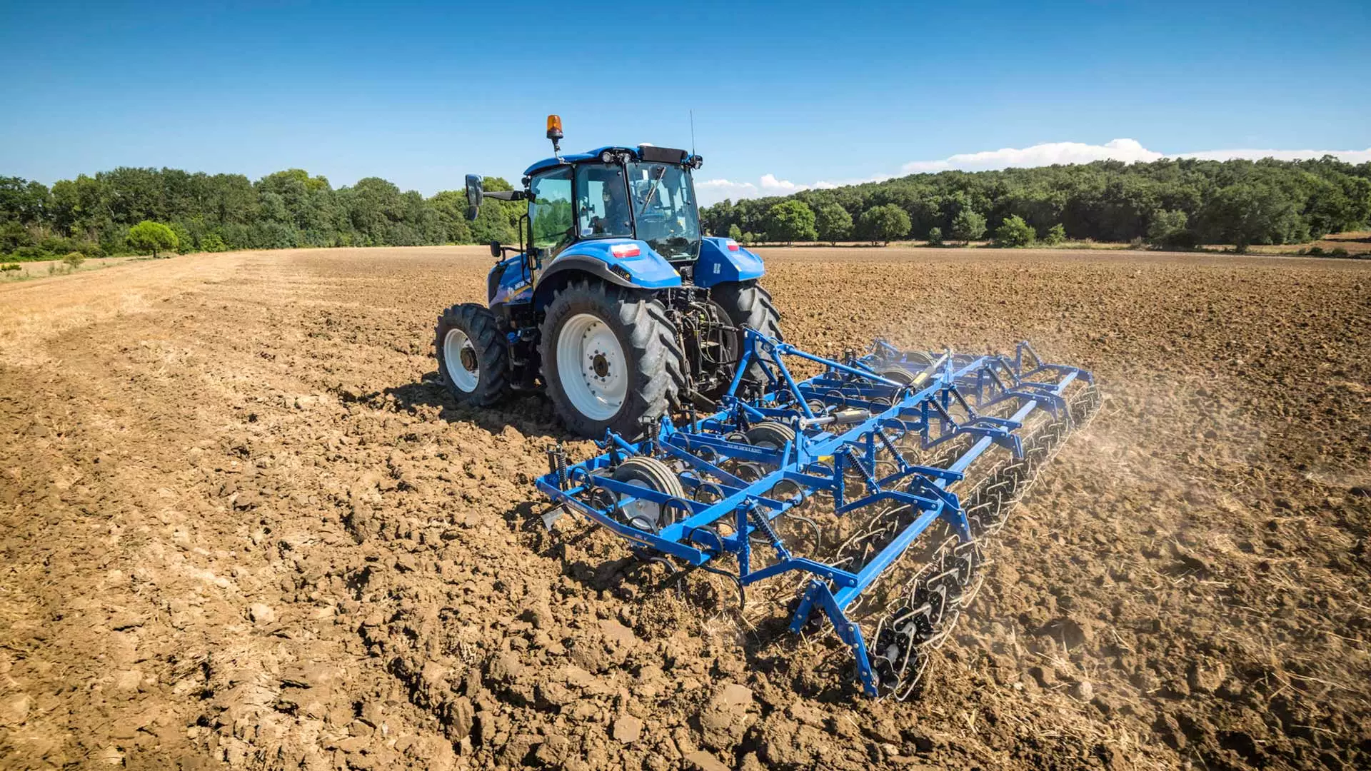 On-field operation of New Holland tractor equipped with spring tine cultivators for soil cultivation