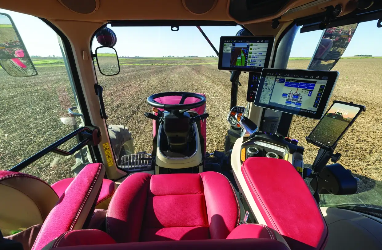View from inside a Case IH Magnum tractor cab overlooking a field. 
