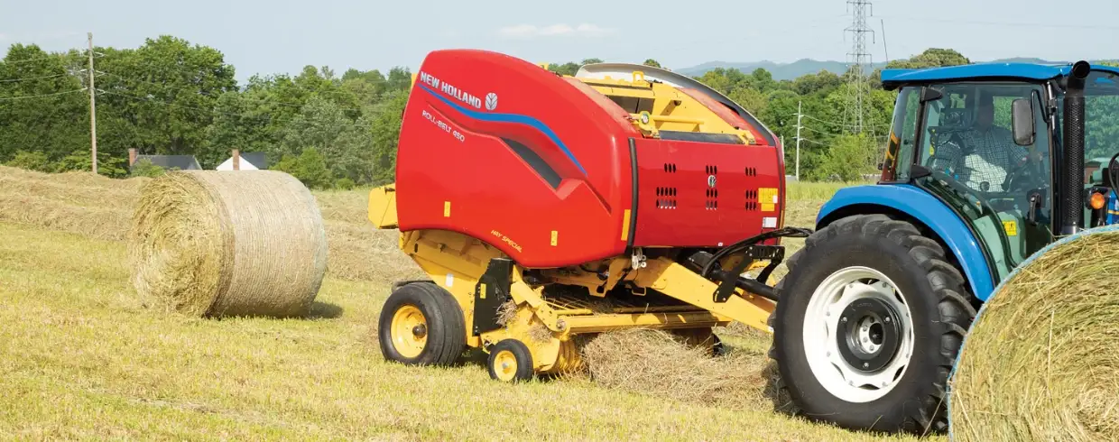 Tractor pulls a Roll-Belt Round Baler in the field