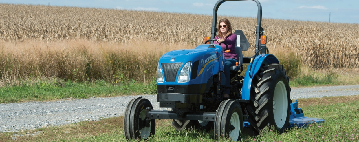 Woman operates WORKMASTER tractor with a mowing attachment