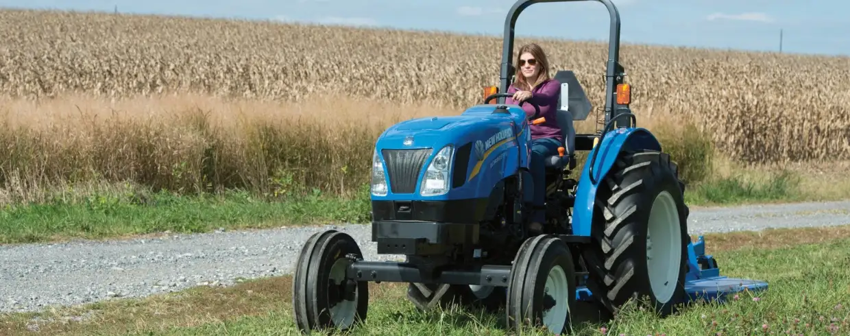 Woman operates WORKMASTER tractor with a mowing attachment