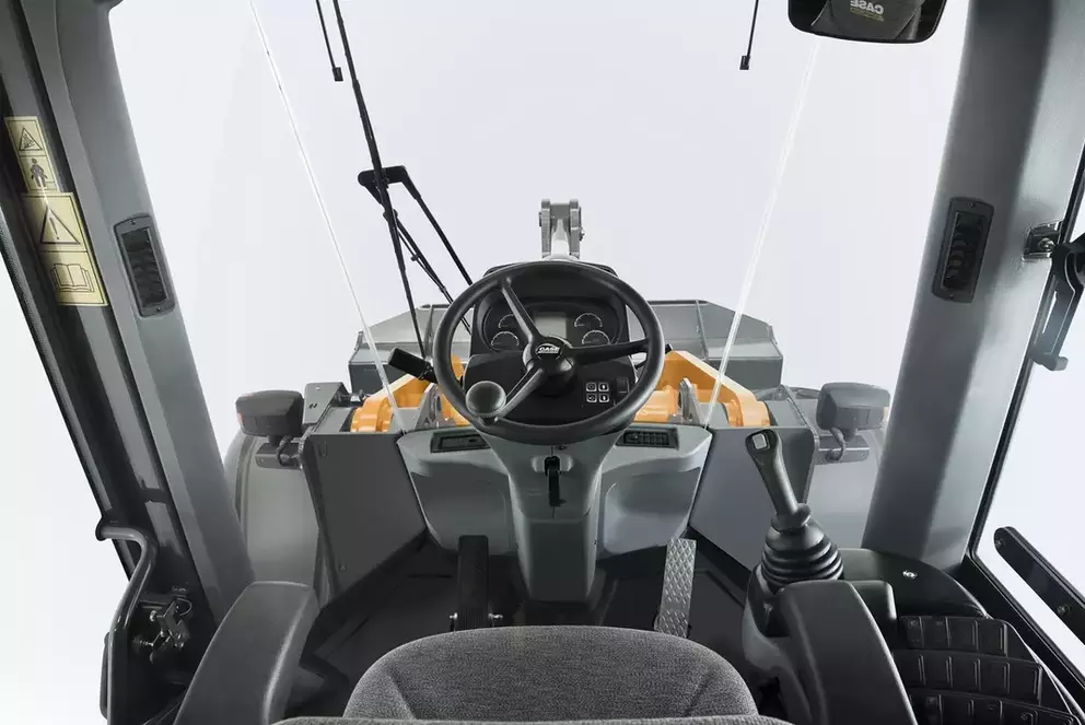 foto de estúdio no interior da cabine da pá-carregadeira Case, com destaque para o volante e o espaço interno.