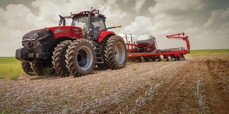 A large Case IH Magnum tractor pulls a Case IH planting implement across a field.